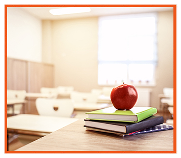 Clean, empty classroom with books and an apple on one of the desks